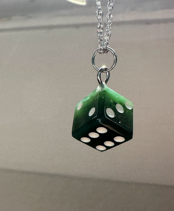 Green dice pendant suspended from a silver chain with rings.