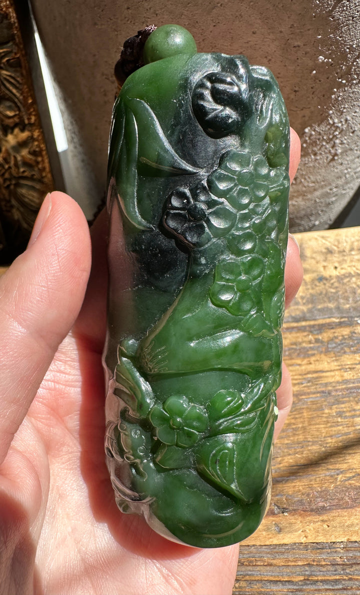 Green Canadian jade hand held pendant carved with flowers and vines in a glossy finish