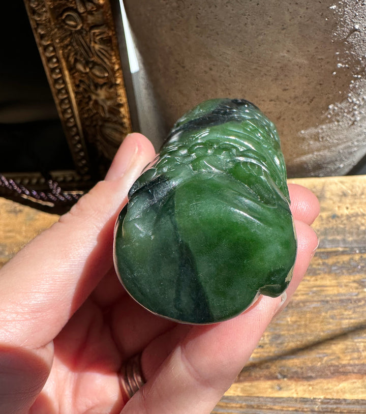 Hand holding a polished Canadian jade chip 3.25 inches, dark green with lighter veins.