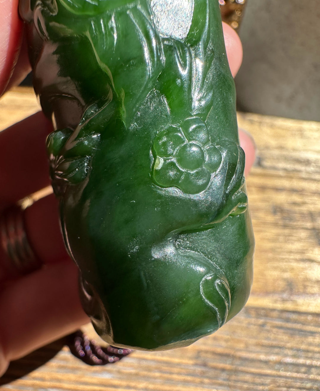 Close-up of green jade carving highlighting a flower motif with leaves and a smooth polished surface