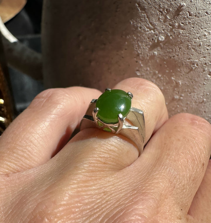 Green jade ring with an oval cabochon worn on a finger