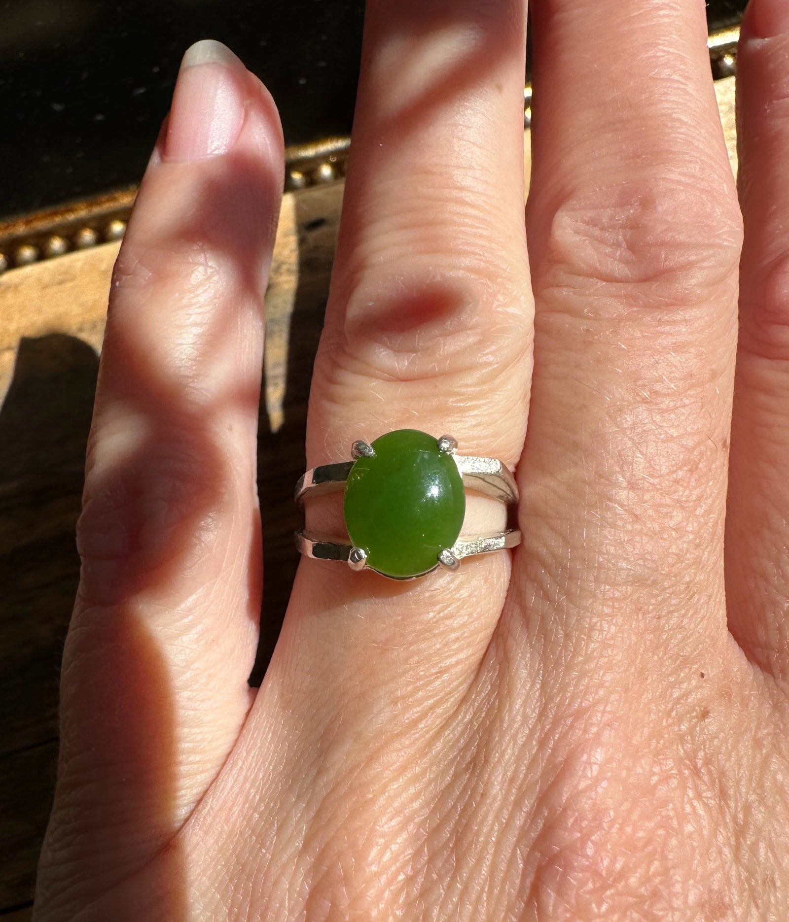 Silver ring with oval green jade worn on the finger