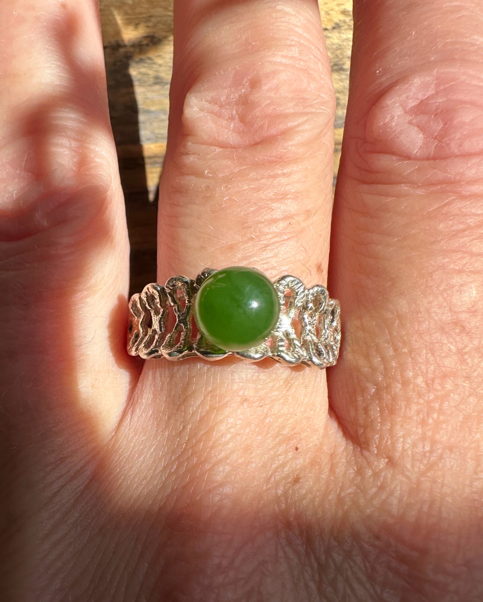 Silver Jade Ring with a round green jade centerpiece worn on a finger