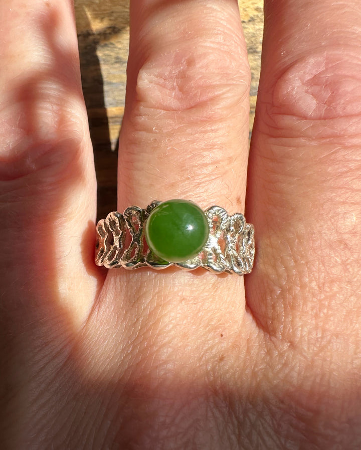 Silver Jade Ring with a round green jade centerpiece worn on a finger