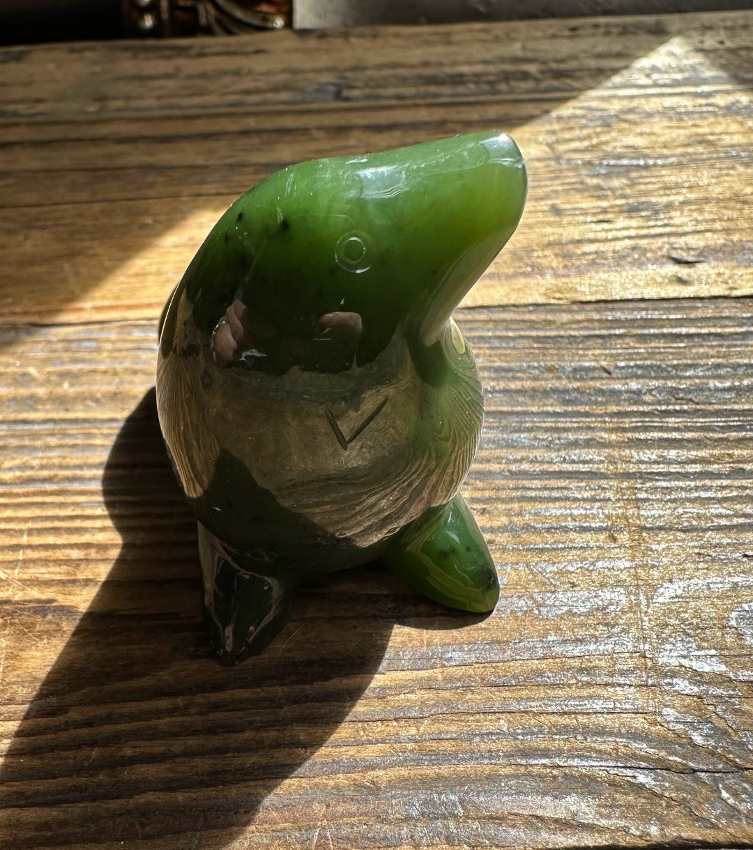 Close up of green jade seal showing glossy head and carved base on wood
