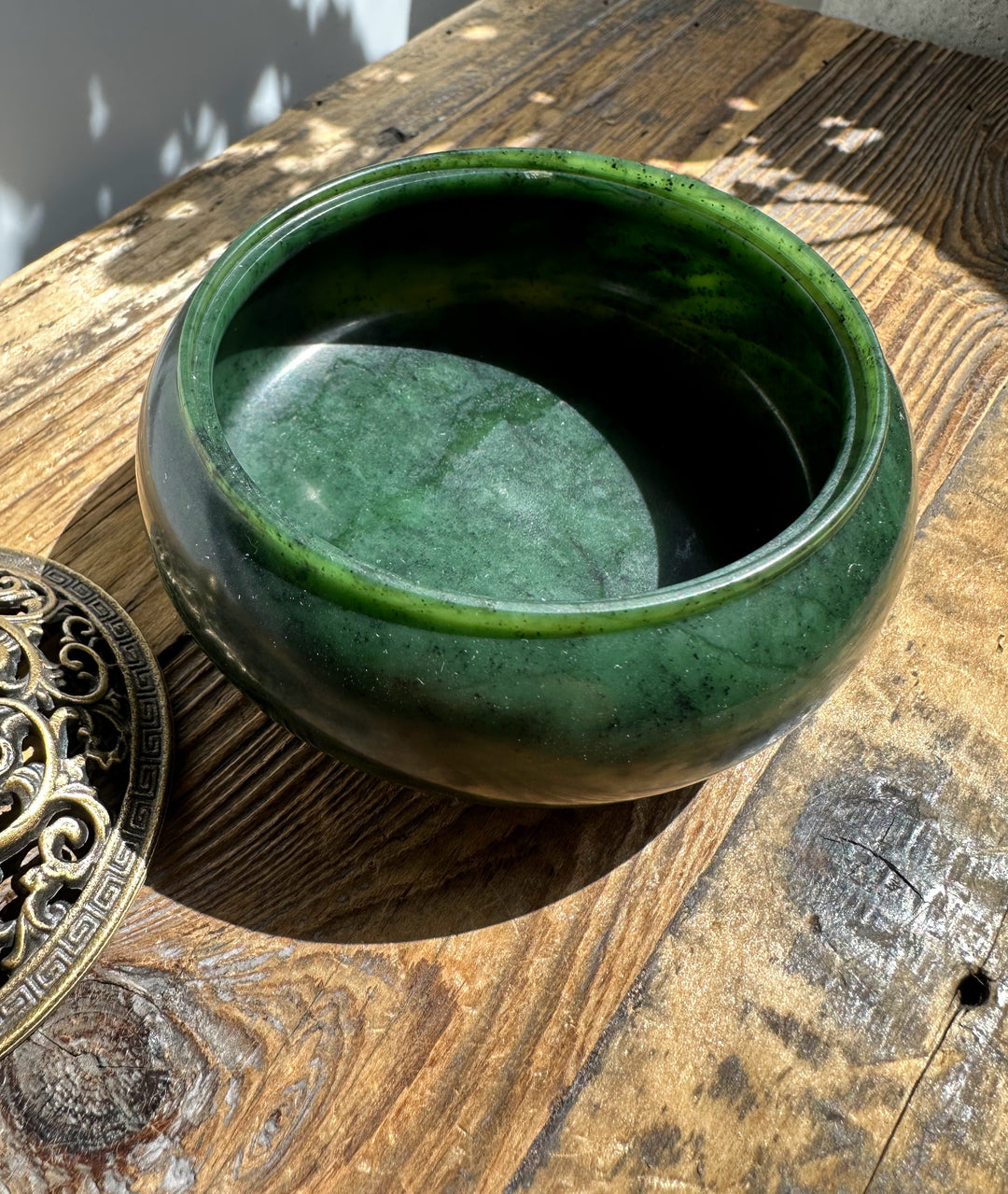 Nephrite jade incense burner bowl in deep green with brass lid off to the side on a rustic wooden surface