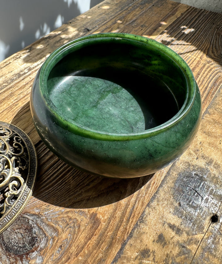 Nephrite jade incense burner bowl in deep green with brass lid off to the side on a rustic wooden surface