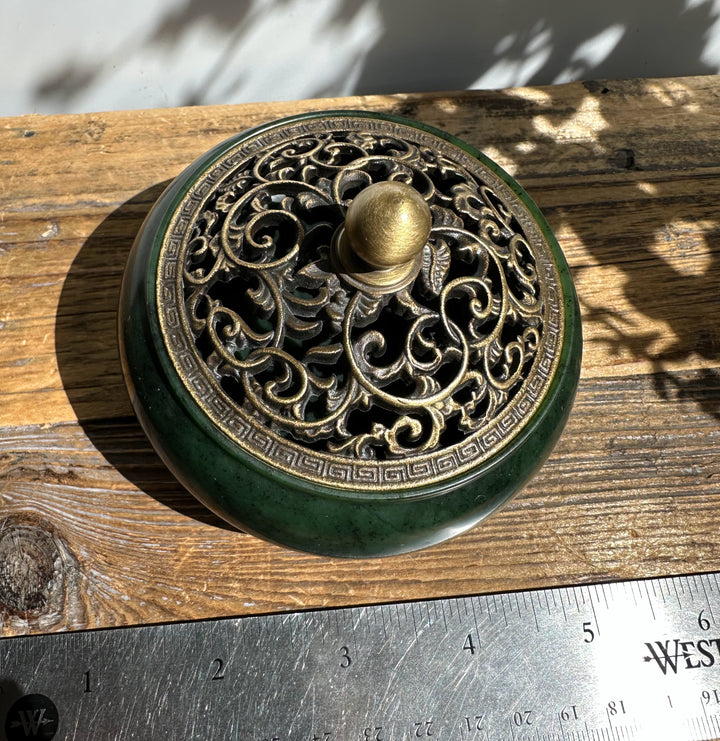 Nephrite jade incense burner with ornate brass lid in place on a wooden surface with a ruler showing scale