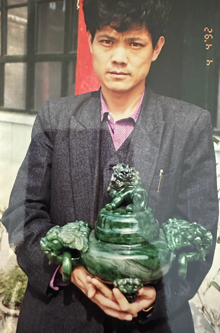 Man in a dark blazer presents a green Polar Jade incense burner with dragon figurines.