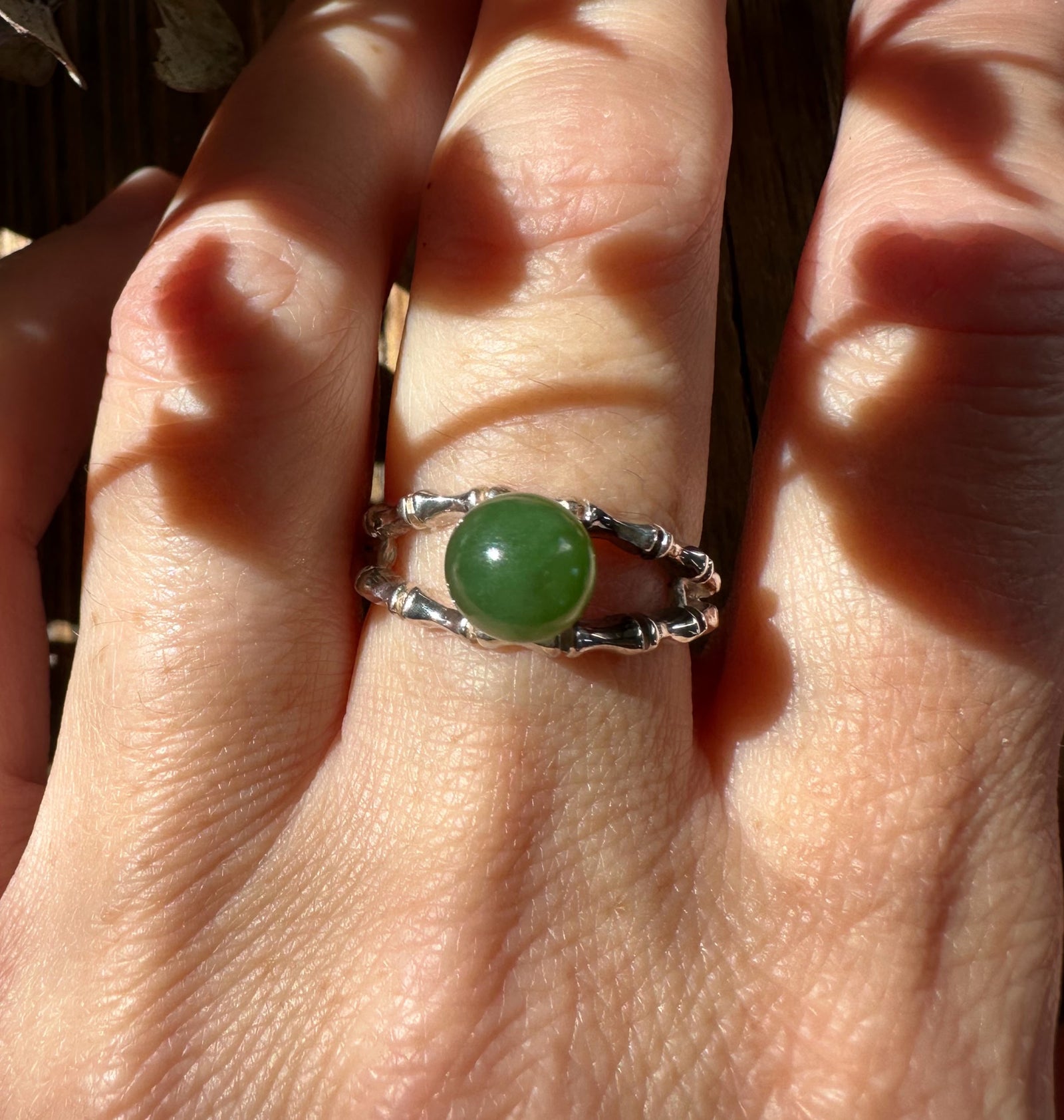 Canadian Jade Ring with round green jade centerpiece on a textured silver double band worn on a finger