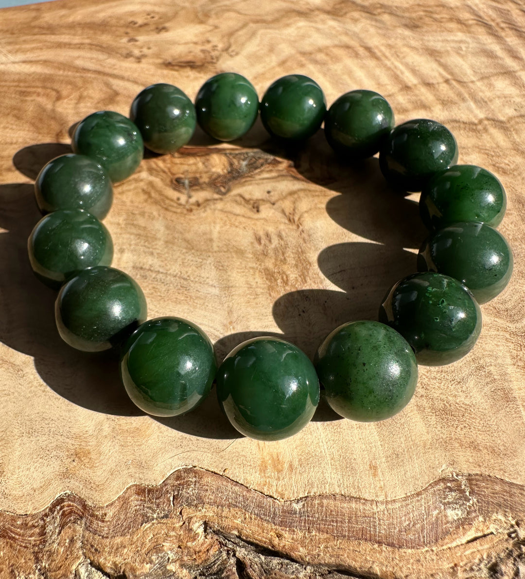14mm Canadian nephrite jade bead bracelet on a wooden surface