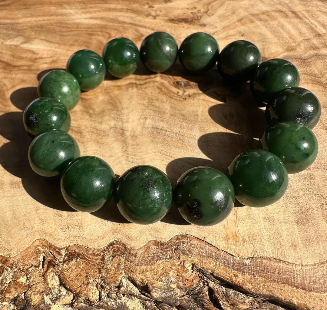 Close up of 14mm Canadian nephrite jade bead bracelet with glossy green beads on wood