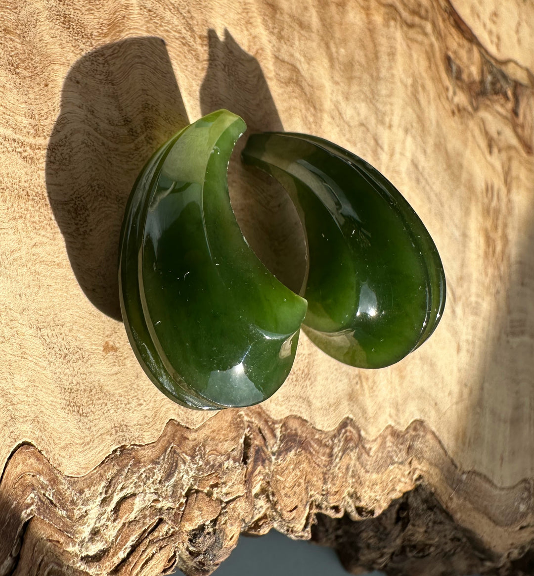 Canandian Jade carved crescent earrings not set viewed from above on wood background