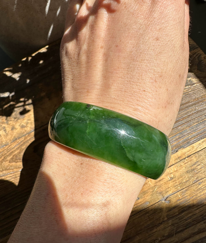 Ogden jade bangle on wrist, polished green stone measuring 57.5 by 22 mm.