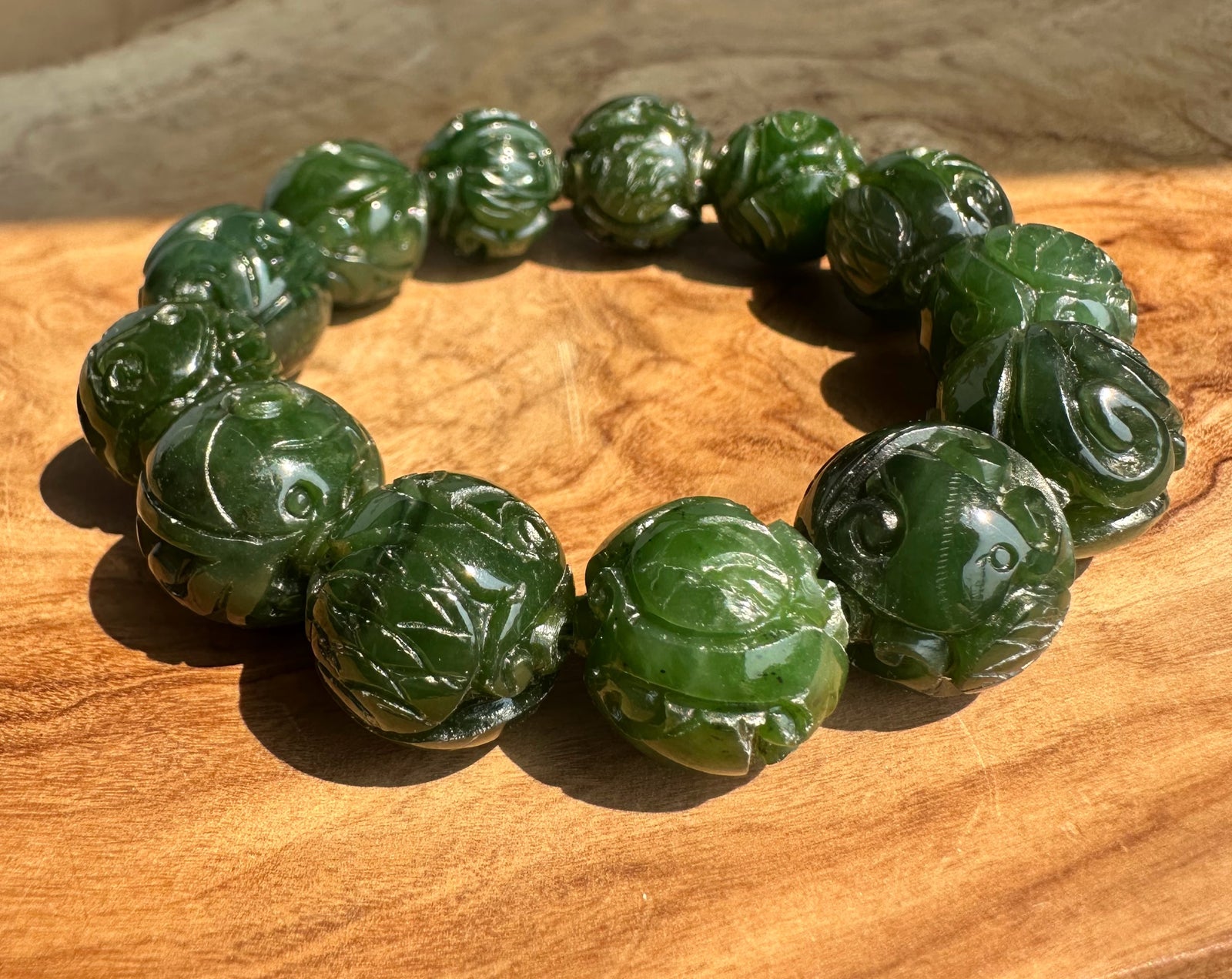 Deep green nephrite jade bracelet with 16mm carved beads arranged in a circle