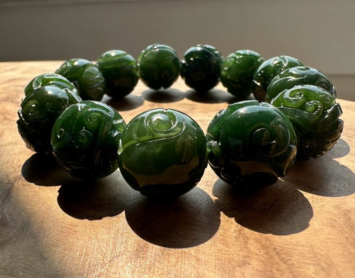 Close up of carved nephrite jade beads with swirling patterns forming a bracelet