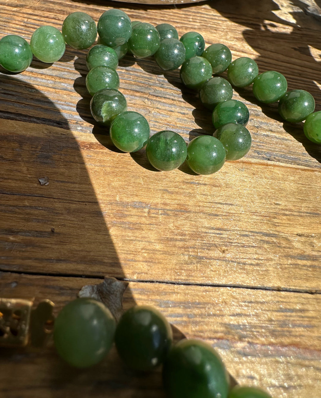 Close-up of round green nephrite jade beads on a weathered wooden surface