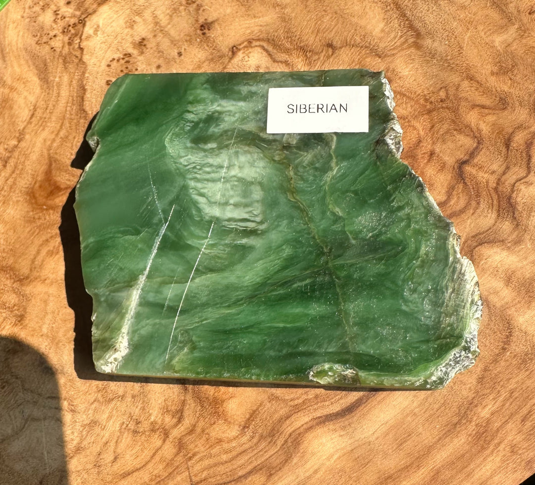 A raw green Siberian jade stone slab with natural marbling and white crystalline edges, labeled &