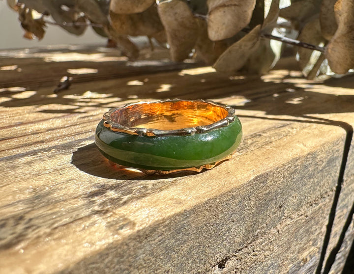 Vintage jade ring with green stone and copper toned inner edge on weathered wood