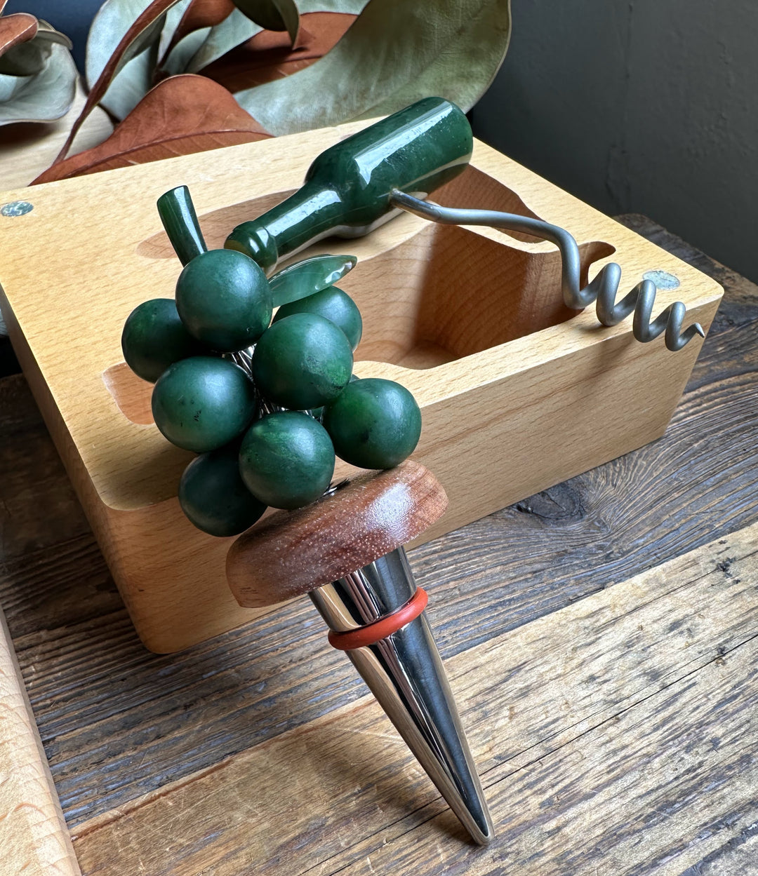 Jade Wine Set opened to reveal a green bottle corkscrew and grape cluster beside the bottle on a wooden box