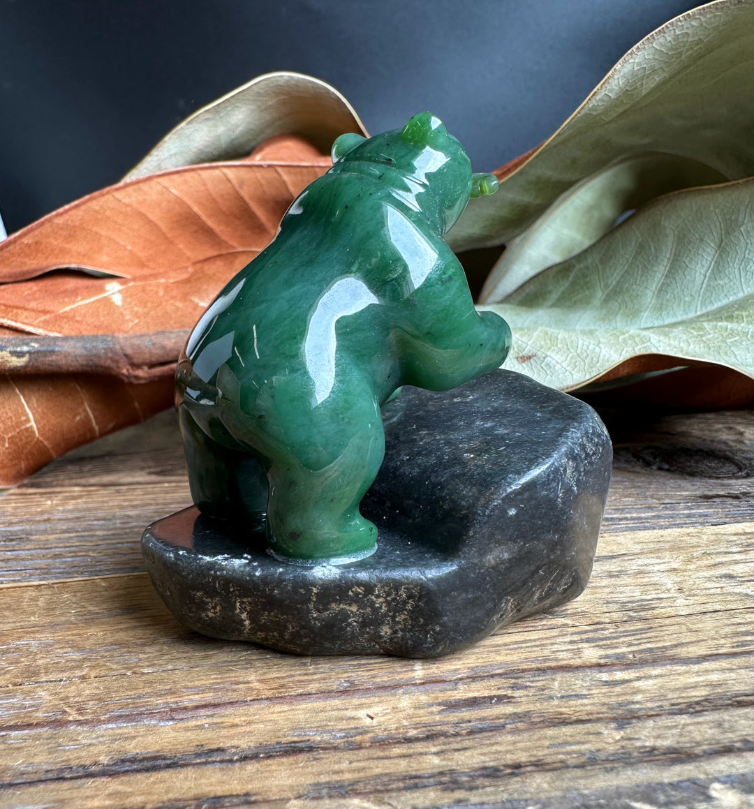 Rear view of the green jade bear on a dark granite base.