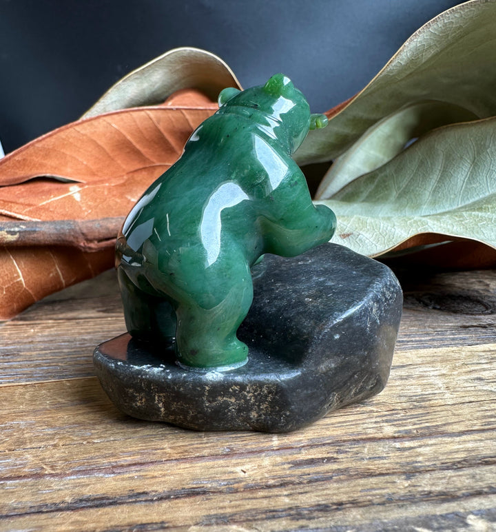 Rear view of the green jade bear on a dark granite base.