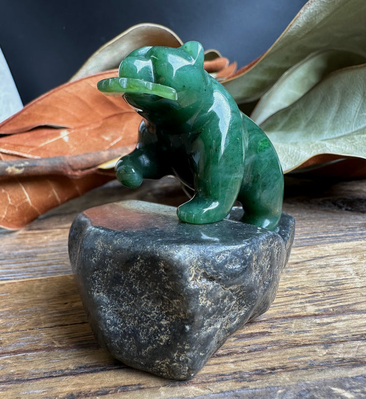 Small jade bear sculpture perched on a dark granite base
