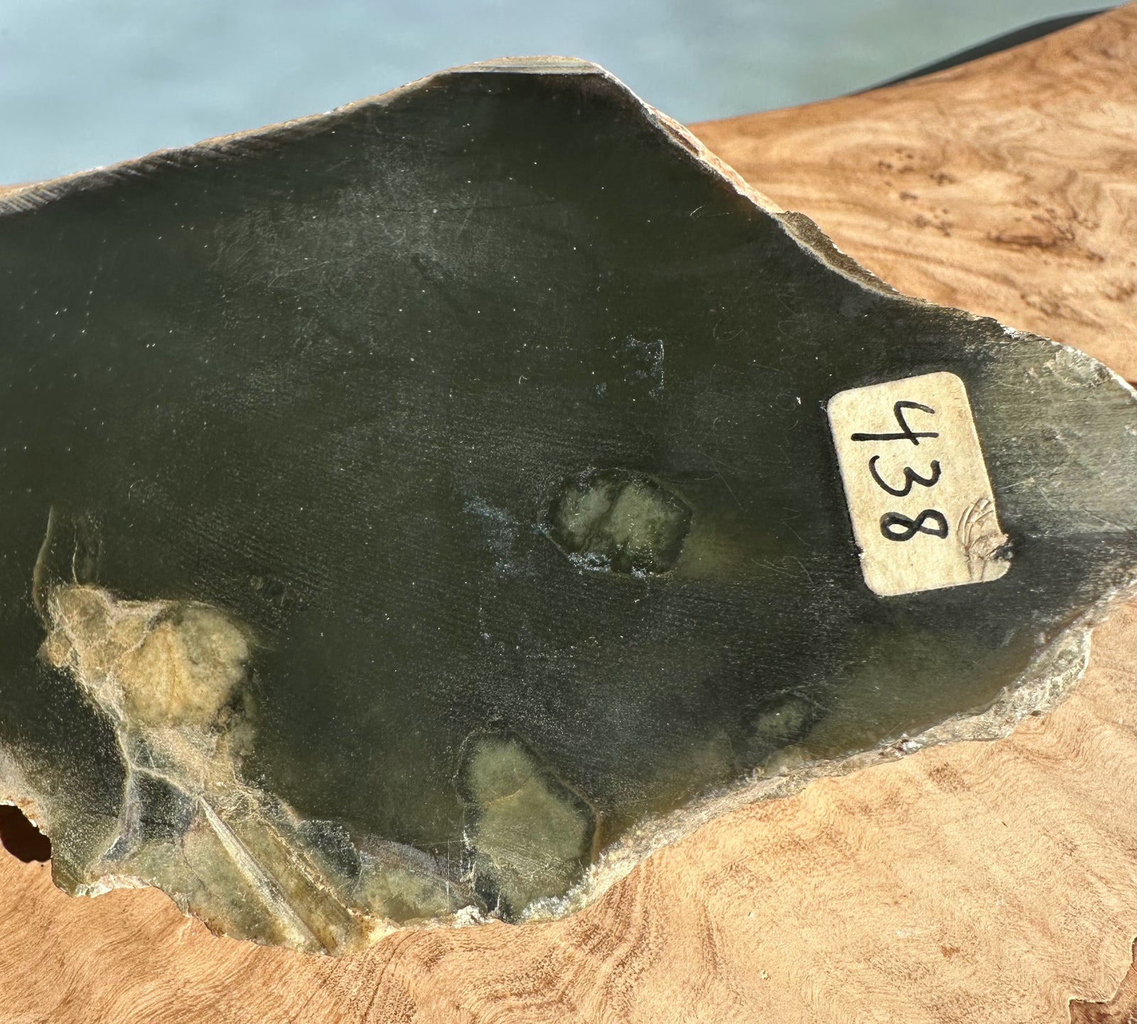 Dark green Wyoming rock slab with rough edge and a beige label reading 438 on a wooden surface.