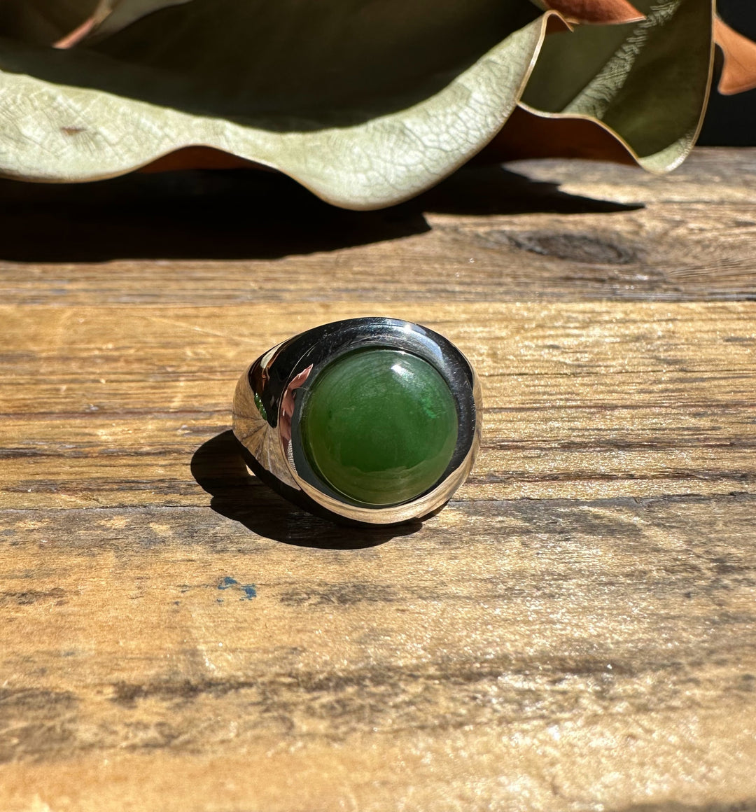 Top view of the Canadian Jade Ring with a vivid green jade stone in a wide polished band.