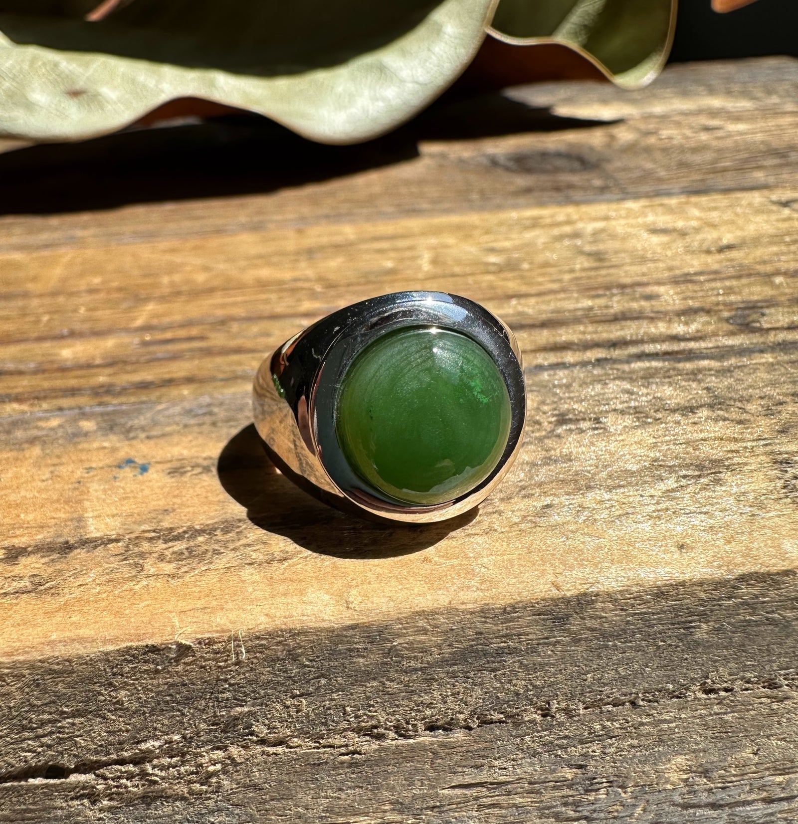 Canadian Jade Ring with green jade cabochon in a bold silver bezel on wood.