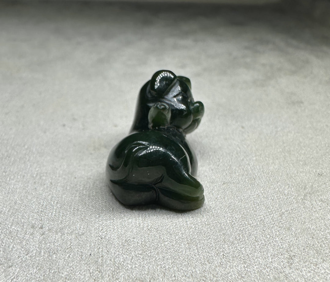 Dark green glossy pig figurine lounging with its back toward the viewer