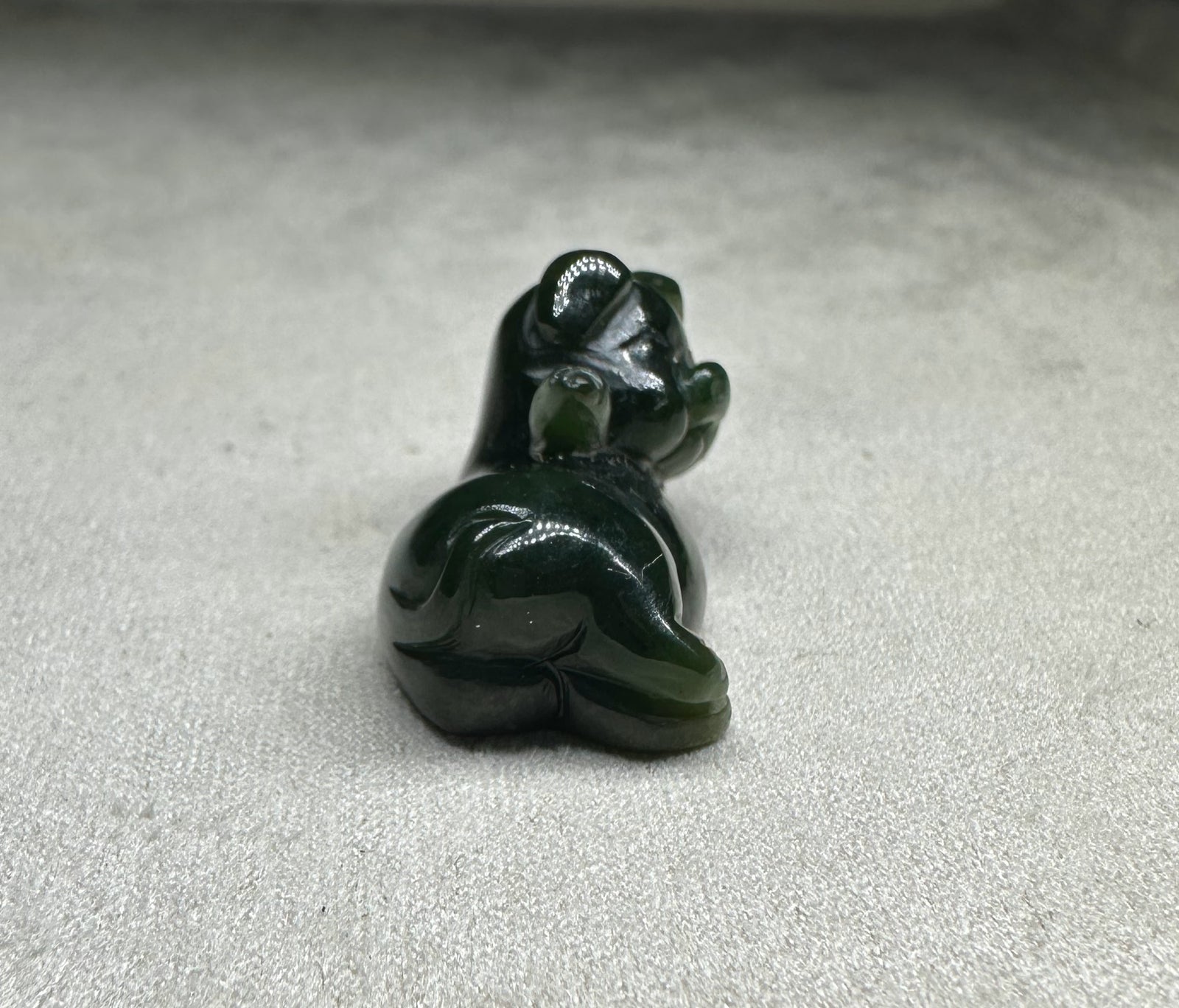 Dark green glossy pig figurine lounging with its back toward the viewer