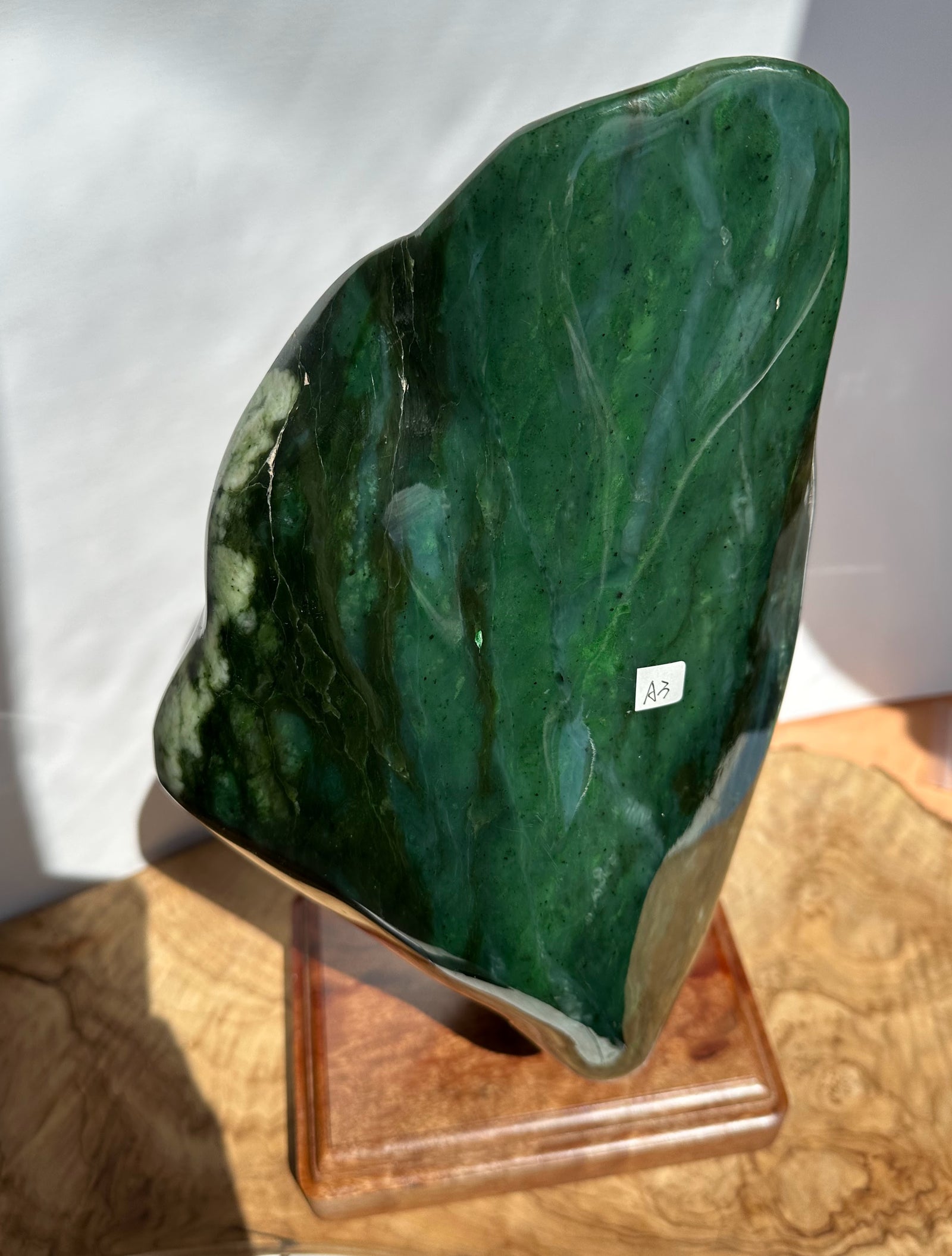 Green Canadian Jade Polished Specimen, on a wooden base and white background