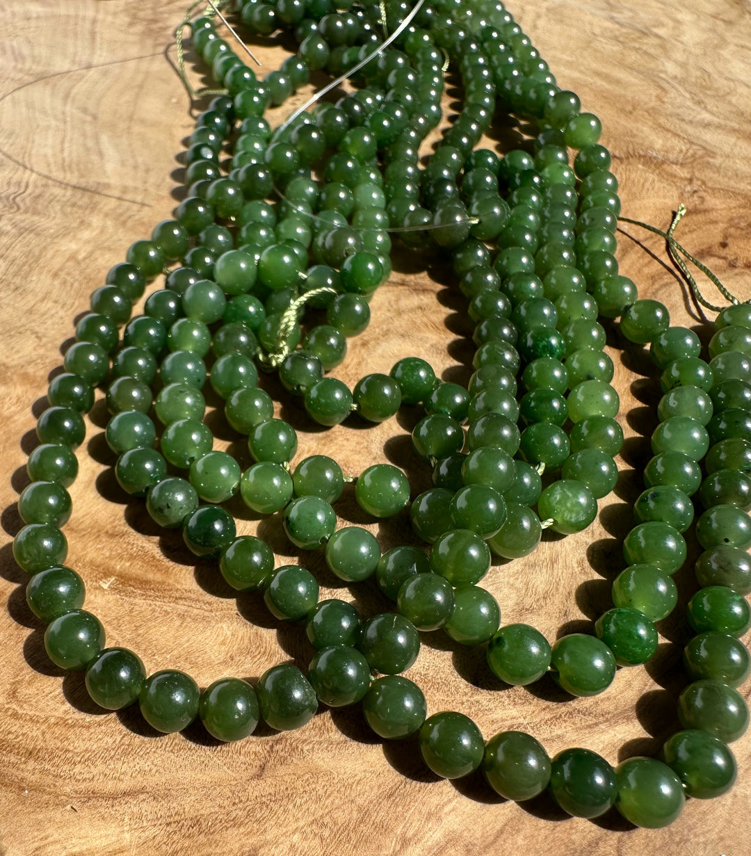 Green jade bead strands arranged on a wooden surface.
