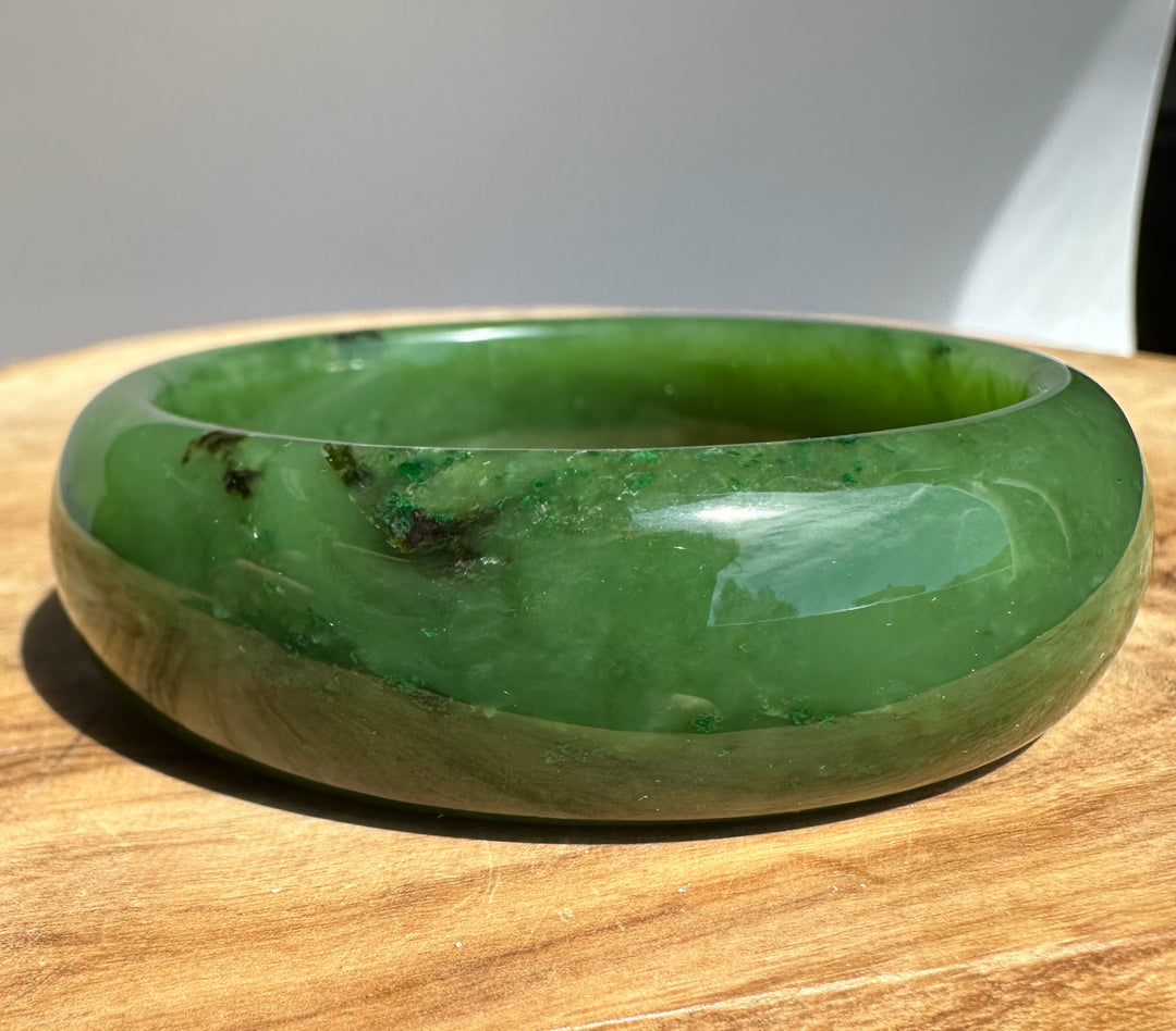 Top view of A Grade Canadian Jade Bangle 57.4 by 19.5 mm showing a glossy green surface.