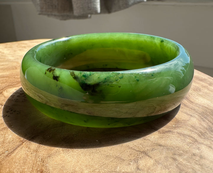 Interior view of a green jade bangle with a bright translucent green interior and smooth inner rim.