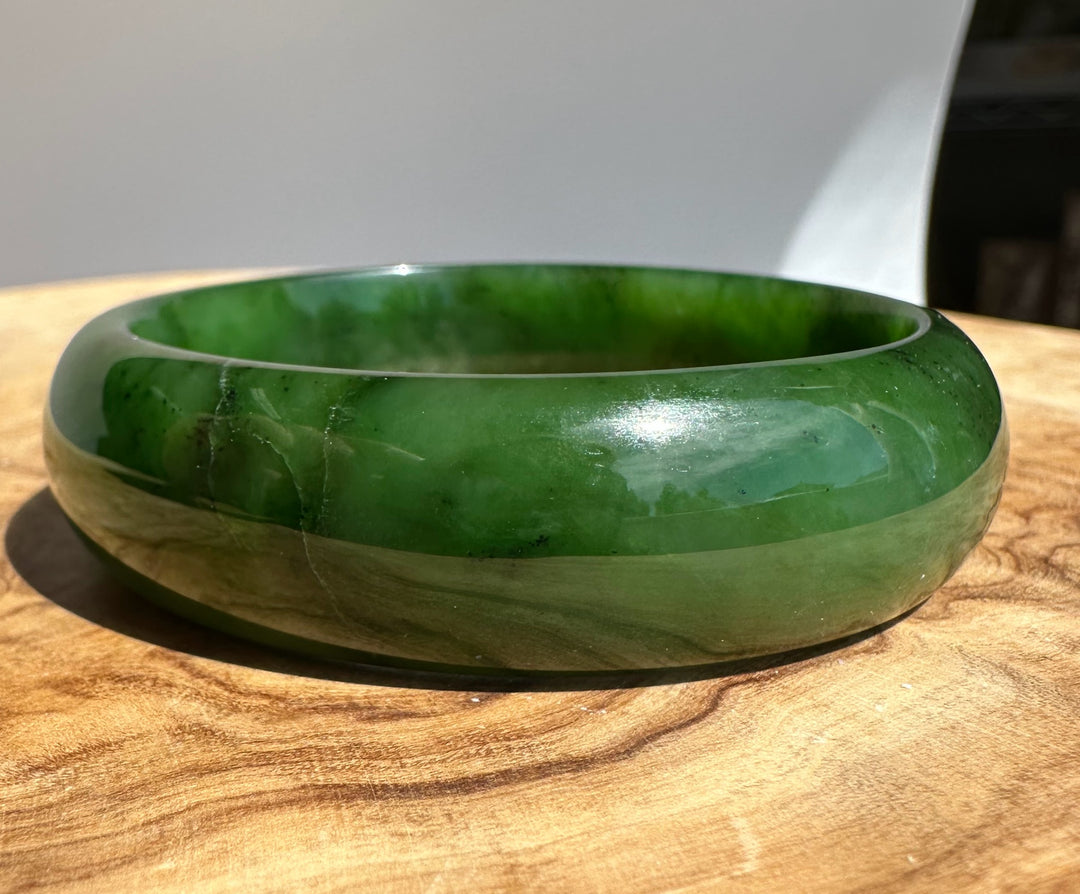 Close up of jade bangle edge highlighting deep green color and glossy finish