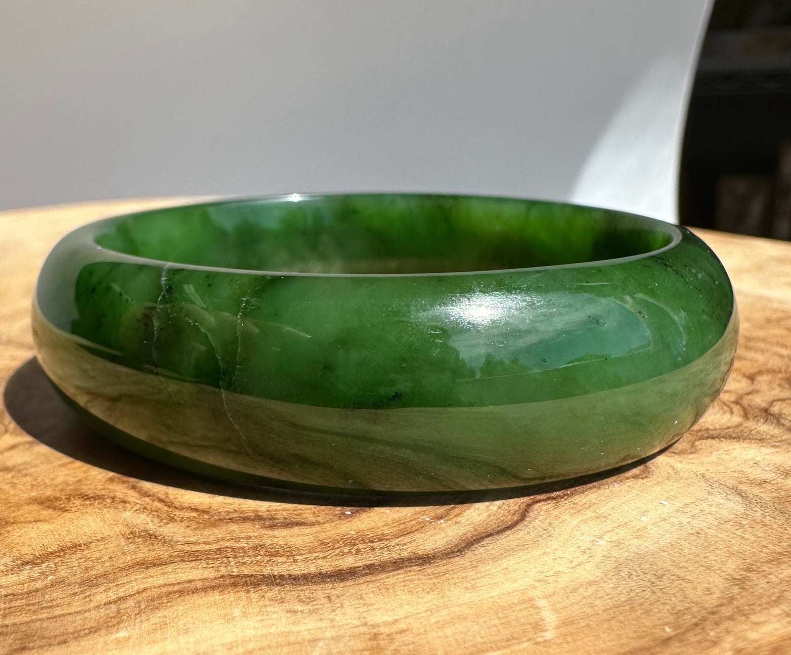 Close up of jade bangle edge highlighting deep green color and glossy finish