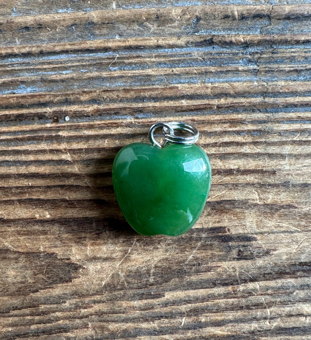 Green apple pendant 14mm with silver bail resting on a rustic wooden surface