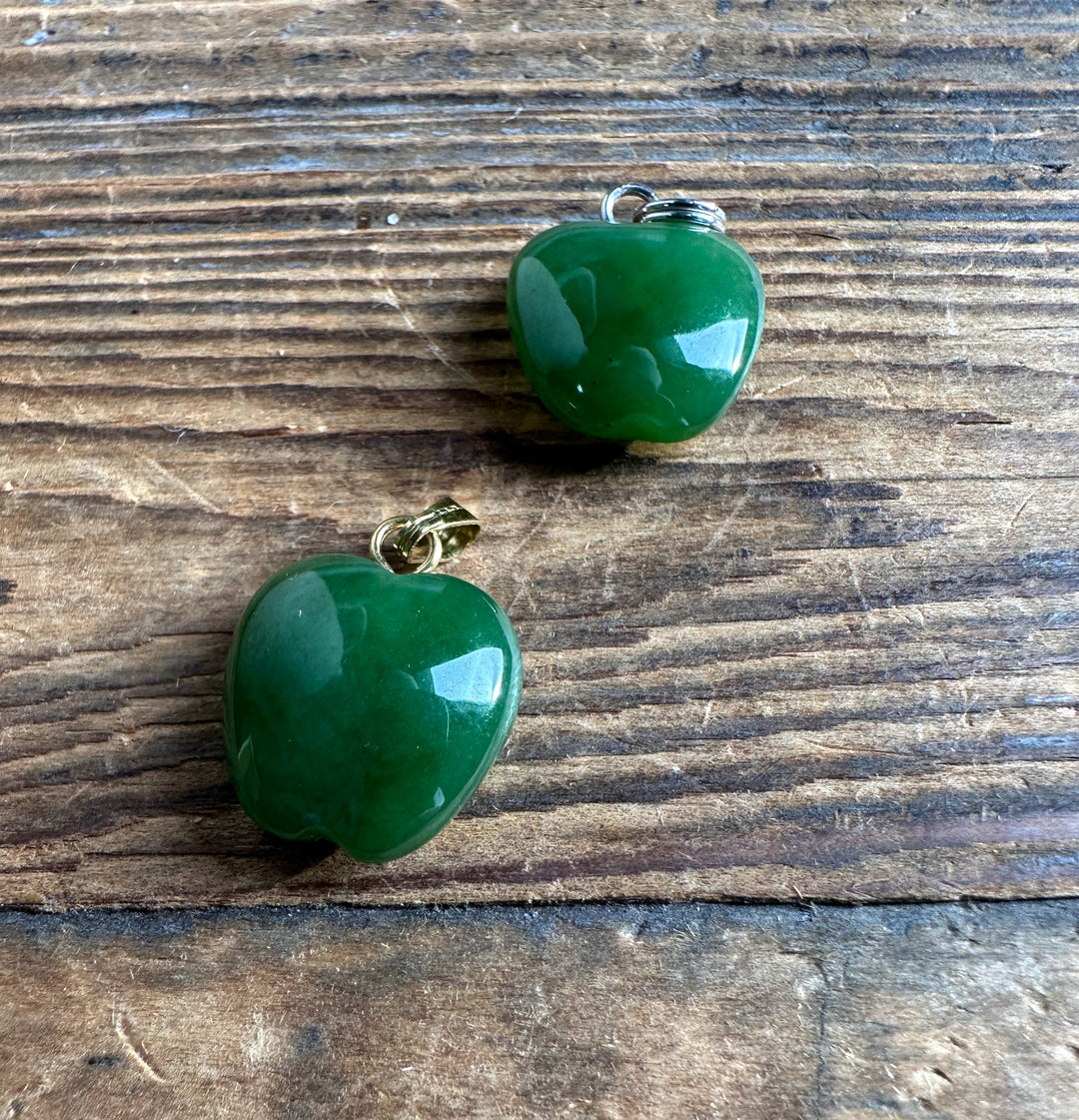 Two green apple pendants 14mm with metal bails on a wooden surface