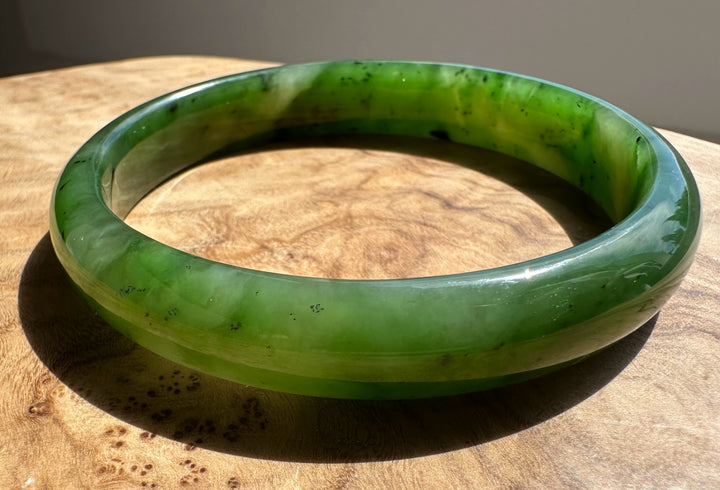 Canadian Jade Bangle 60 x 11mm viewed from the side with a rich green hue and dark flecks