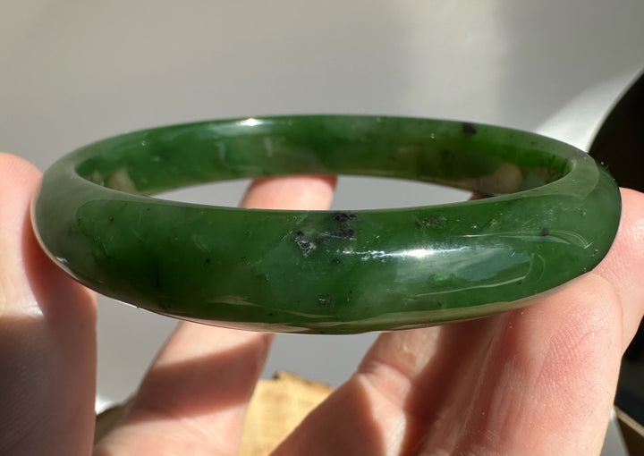 Canadian Jade Bangle 60 x 11mm held between fingers showing the vivid green color and smooth interior