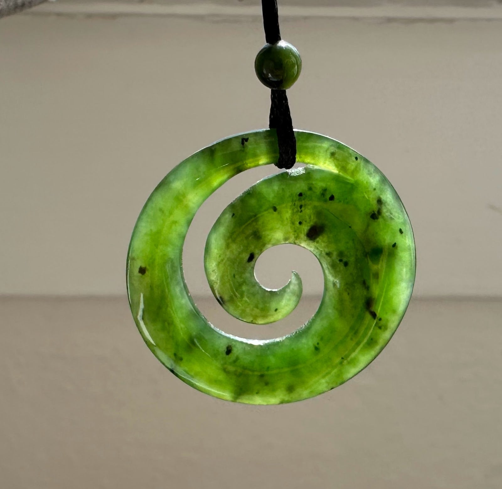 Close-up of green jade spiral pendant highlighting the donut shape and natural color variations