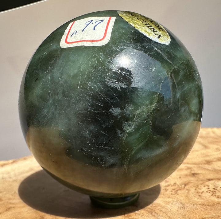 Canadian Jade 66mm sphere with a white label outlined in red and a gold seal affixed to its surface