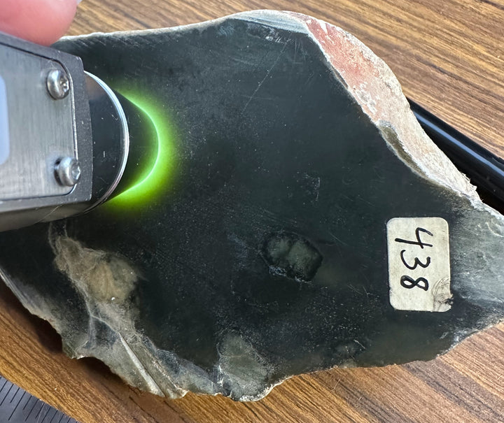 Wyoming rock sample with a green glow from a handheld sensor and a label reading 438