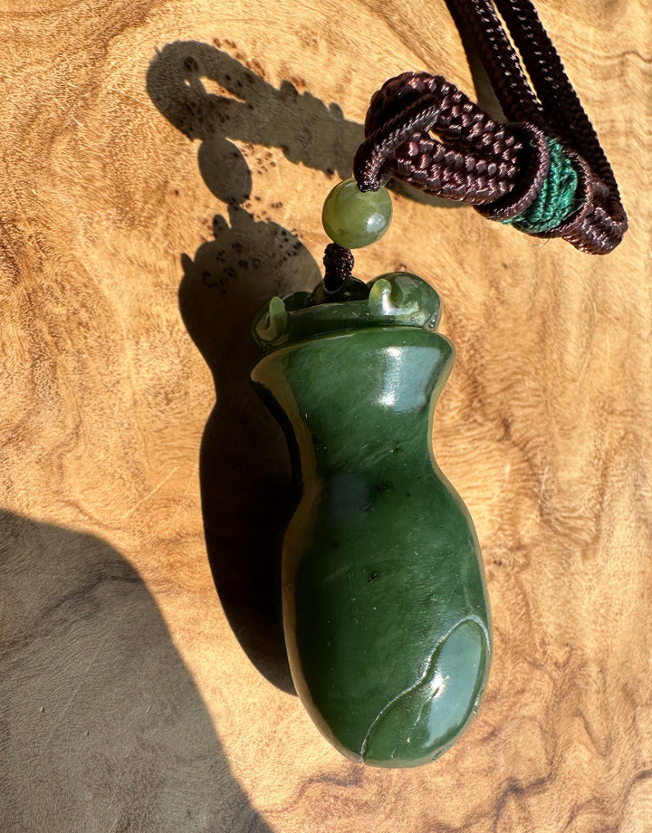 a dark green jade pendant on a wooden base