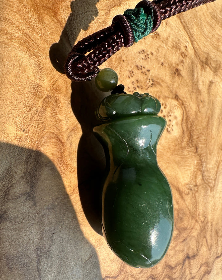 Dark Green jade pendant on a wooden base