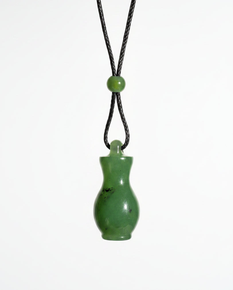 A small green jade bottle pendant on a black cord, white background