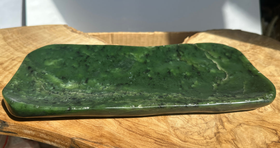 Green jade nephrite dish on a wooden slab