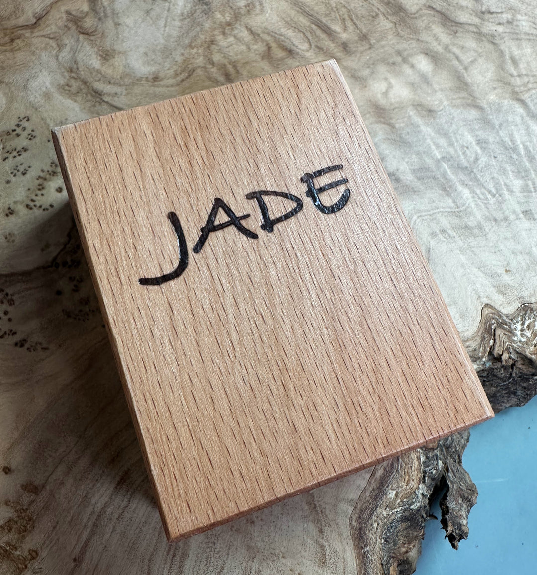 Square wooden gift box lid engraved with JADE THE STONE OF HEAVEN and a descriptive inscription.